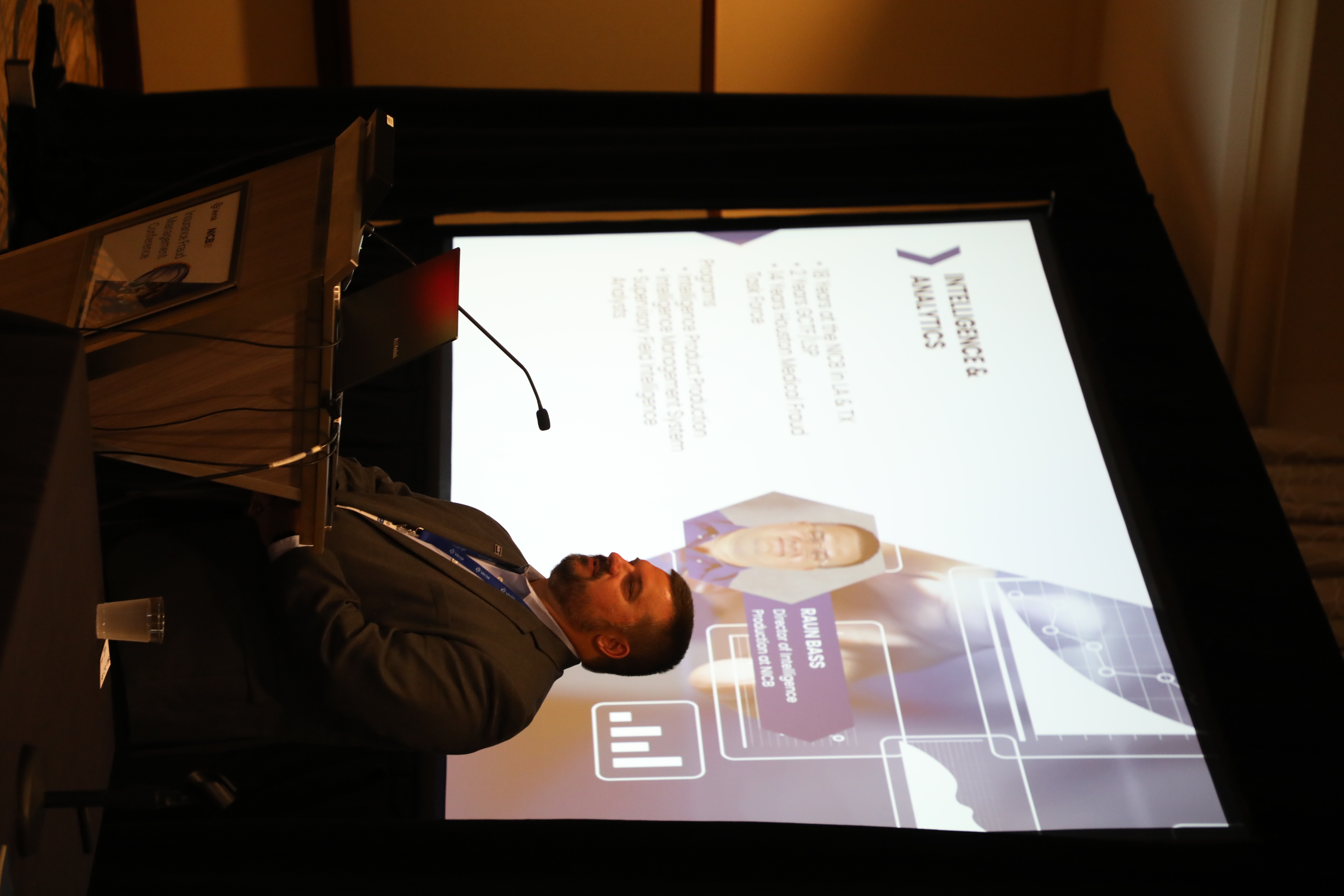 A light-skinned man with a beard stands in front of a slide around intelligence and analytics.