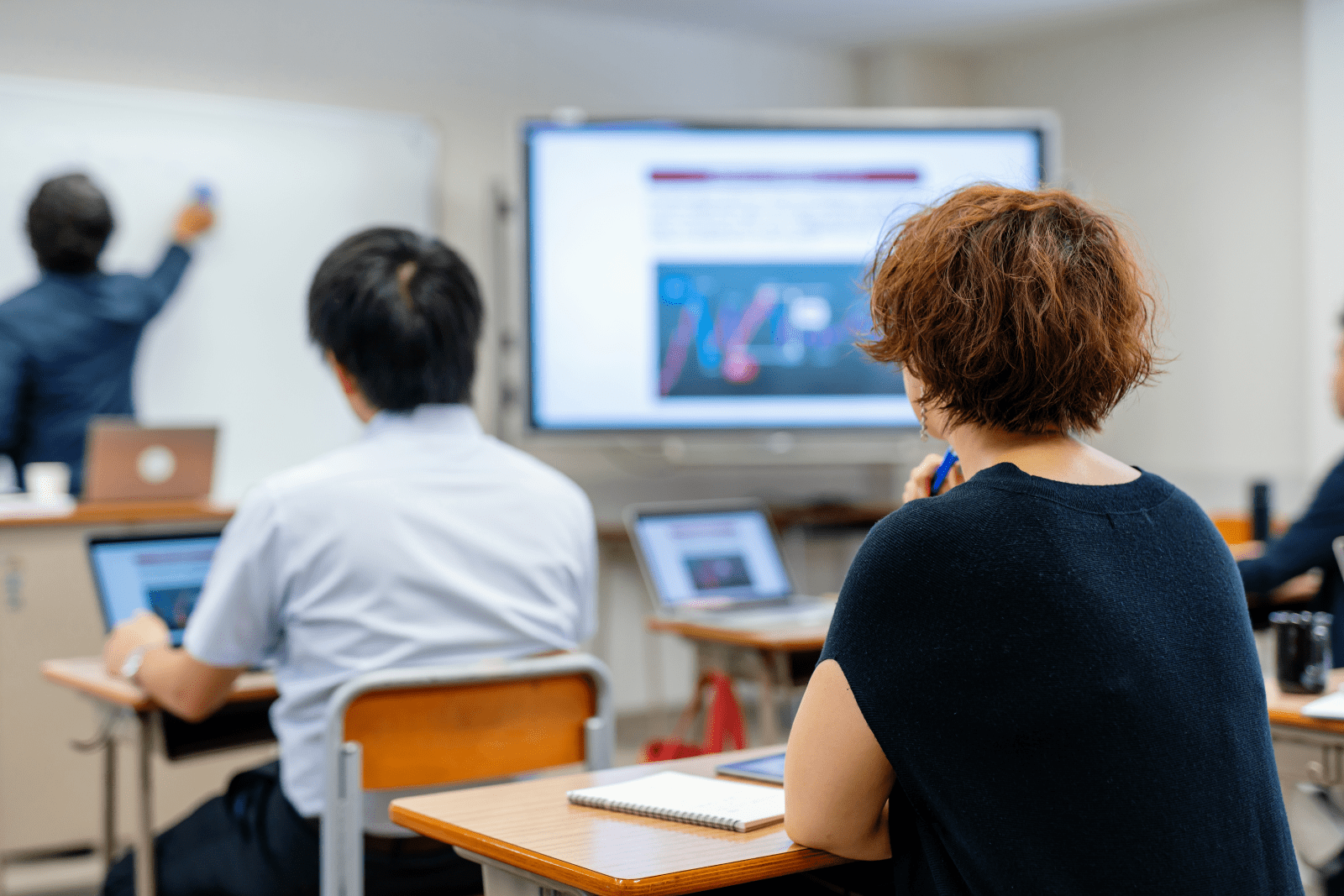 People sitting in a classroom looking at a whiteboard