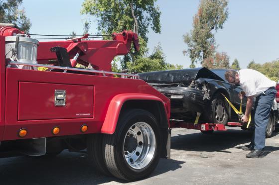 Red tow truck towing black car