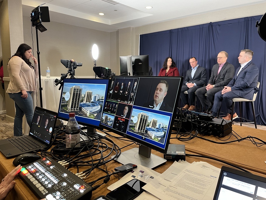 A group of NICB leaders sit together for a broadcast interview, surrounded by lights, computers, cameras, and so on.